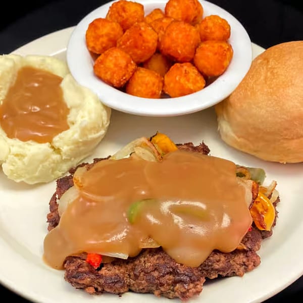 Myra Jean's Salisbury steak with gravy, mashed potatoes, tater tots, and a dinner roll.