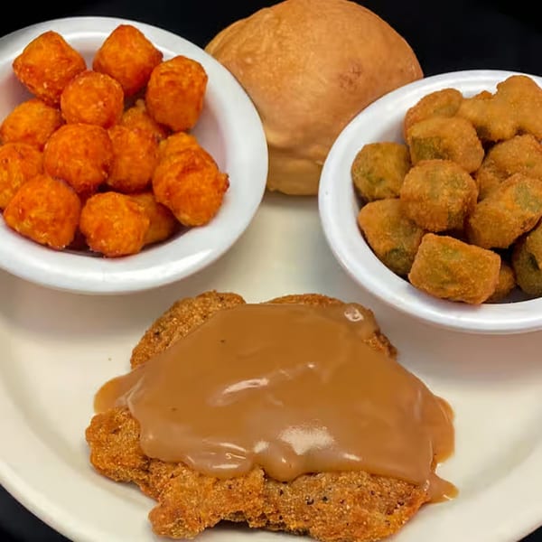 Myra Jean's American meal with chicken fried steak, gravy, tater tots, fried okra, and a roll.