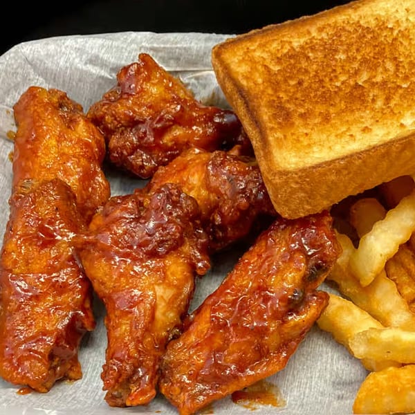 Myra Jean's BBQ chicken wings with a side of golden french fries and toasted bread.